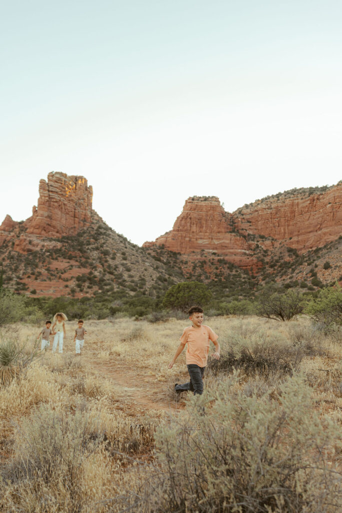 Child running through the desert during a playful Sedona family photo session surrounded by iconic red rock scenery.