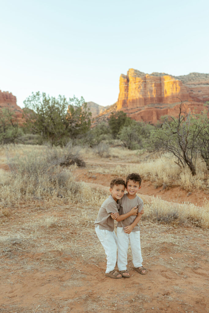Two brothers hugging during an outdoor family photography session in Sedona featuring Arizona's breathtaking desert landscape.