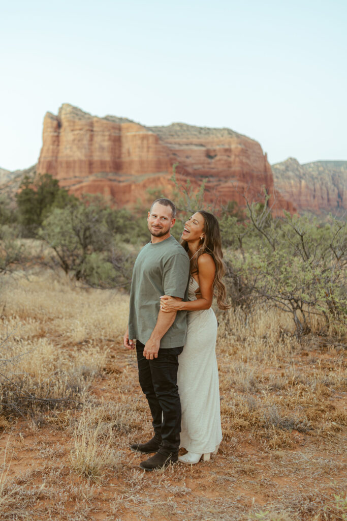 Romantic couples portrait in Sedona featuring a husband and wife embracing with Cathedral Rock and Arizona's red rock scenery behind them.