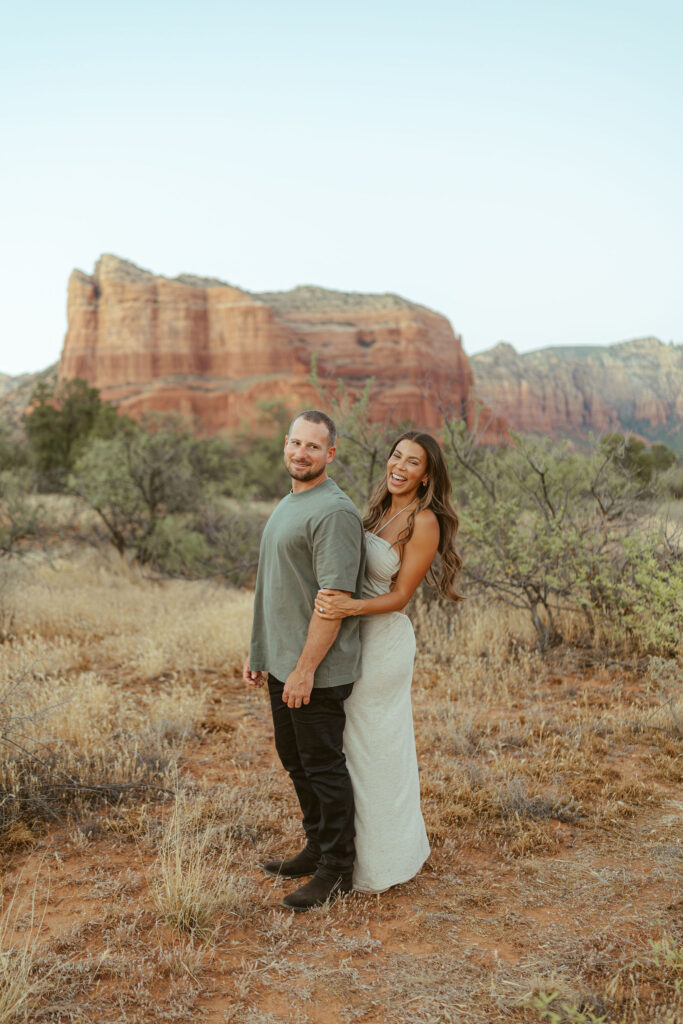 Couple embracing during a golden hour Sedona photography session with panoramic red rock views in the background.