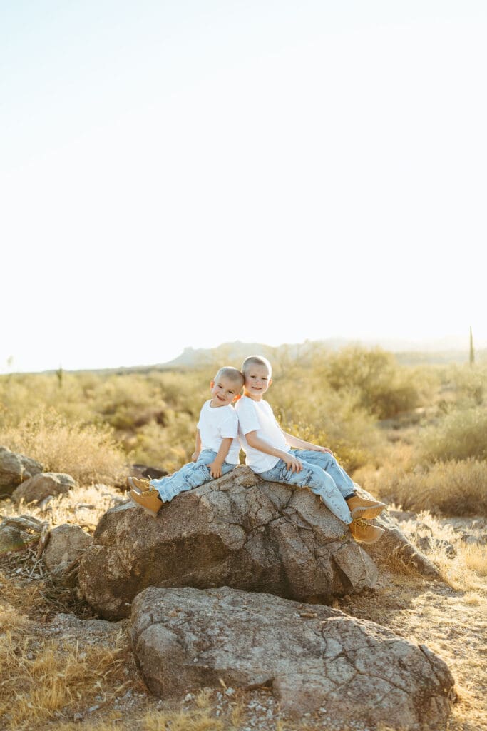 Brothers sitting together on desert rocks during a Superstition Mountains pregnancy announcement session