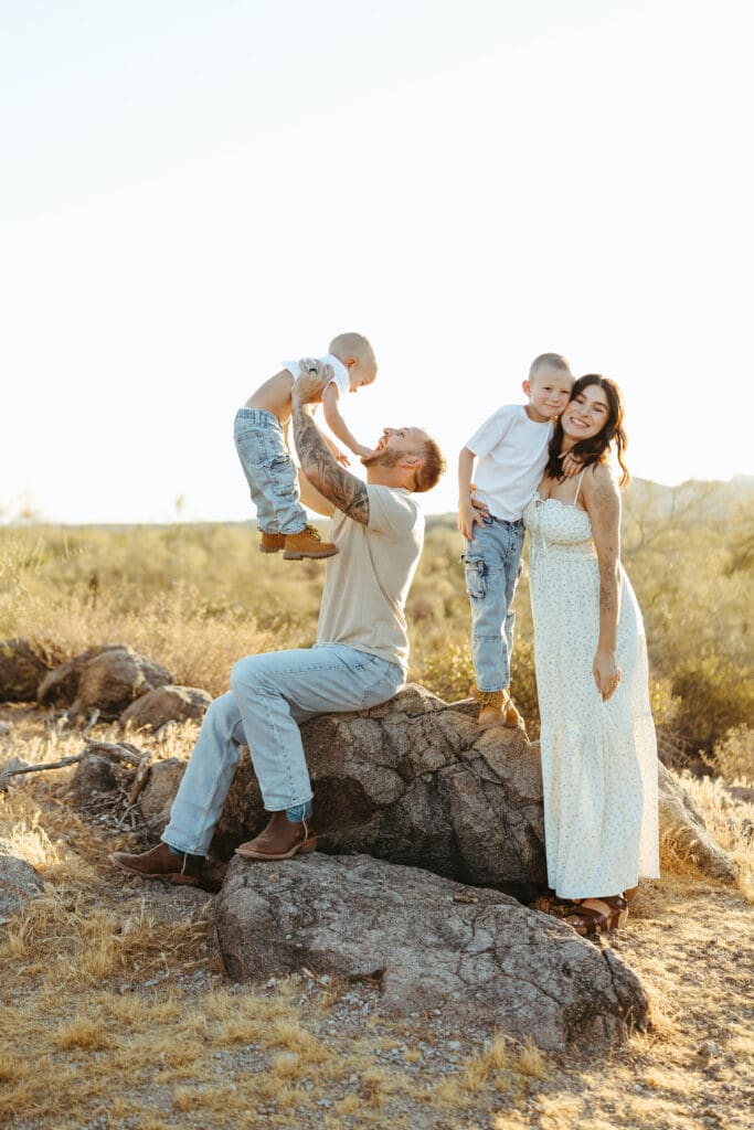 Dad lifting his son during a Scottsdale pregnancy announcement photography session in the Arizona desert