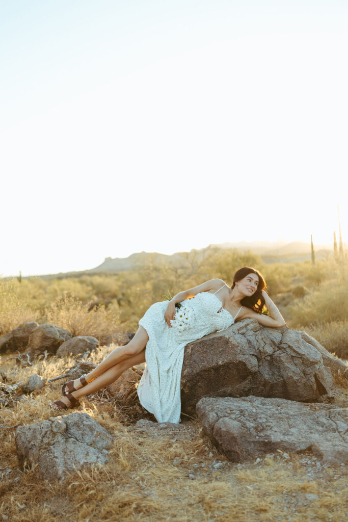 Expecting mother relaxing on desert rocks during a Scottsdale maternity photography session