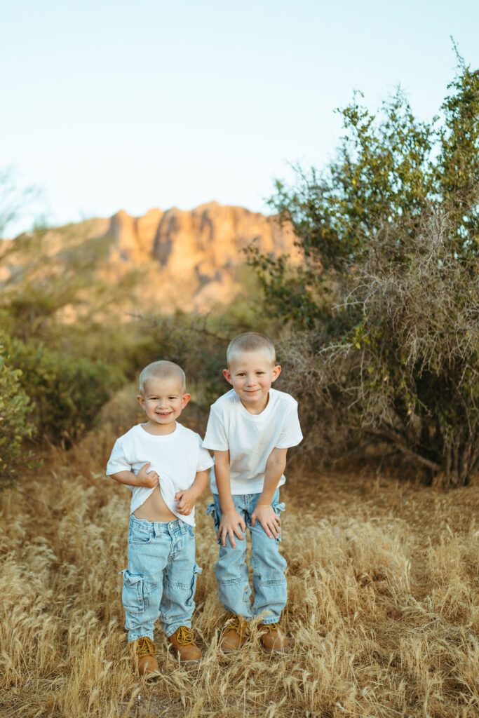 Two brothers smiling in front of the Superstition Mountains during a Scottsdale pregnancy announcement session