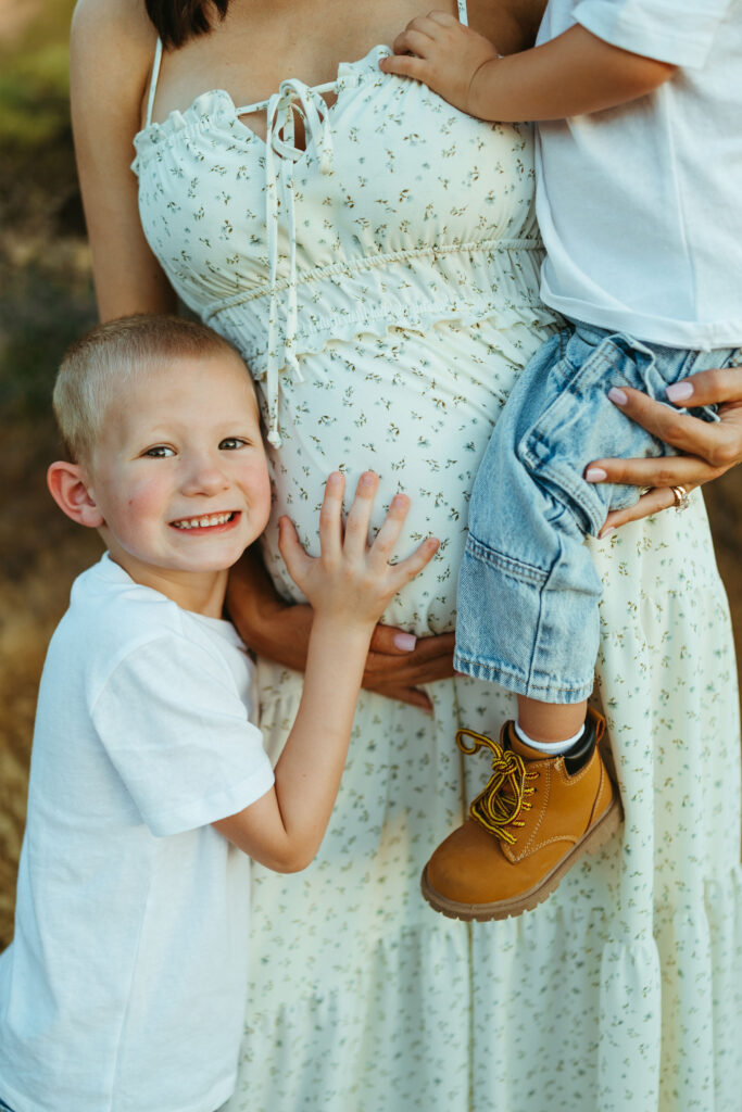 Big brother hugging his mother's baby bump during a Scottsdale maternity photography session