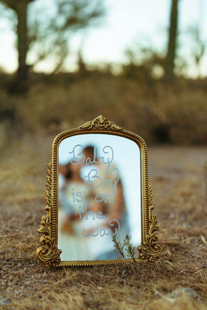 Pregnancy announcement mirror reading "Baby Boy is on the way" in the Arizona desert