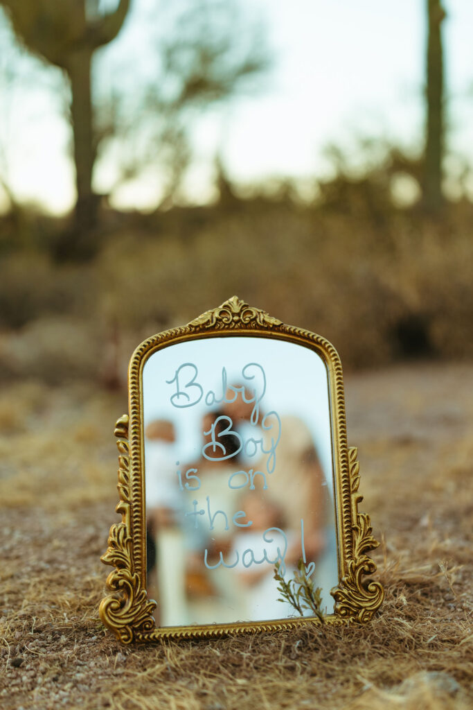 Mirror pregnancy announcement surrounded by desert landscape at the Superstition Mountains