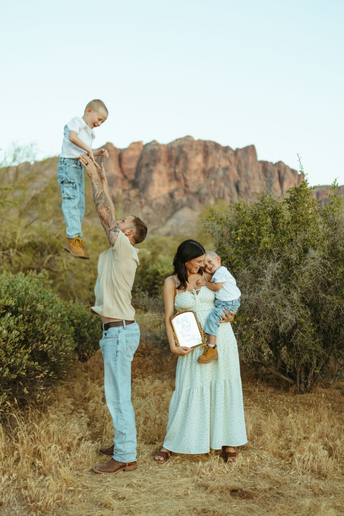 Family celebrating their pregnancy announcement with the Superstition Mountains in the background