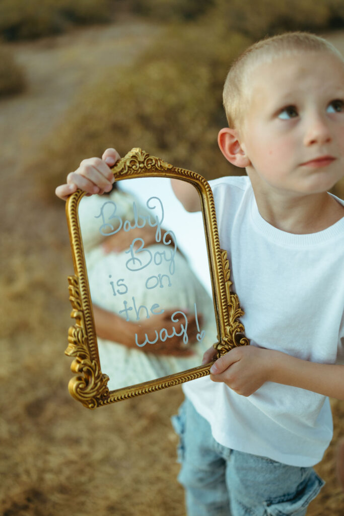 Big brother holding pregnancy announcement mirror during a Scottsdale pregnancy announcement photo session