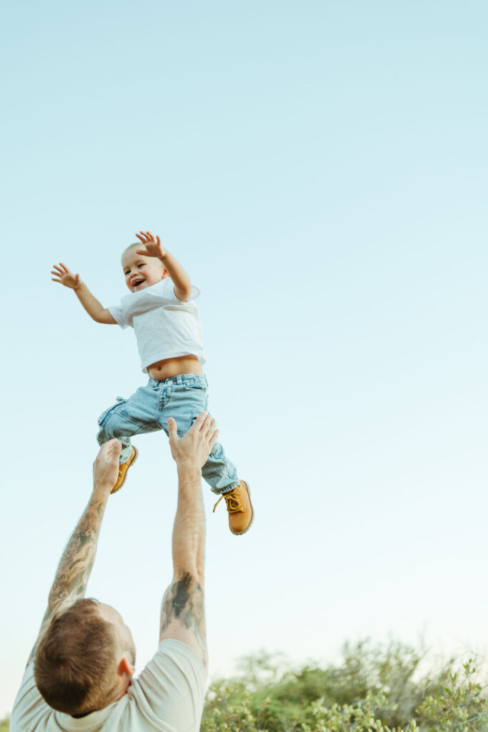 Dad tossing his son into the air during a fun family maternity session in Scottsdale, Arizona