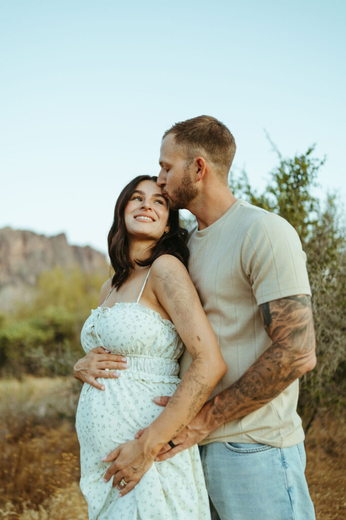 Expecting parents embracing during a romantic Superstition Mountains maternity session