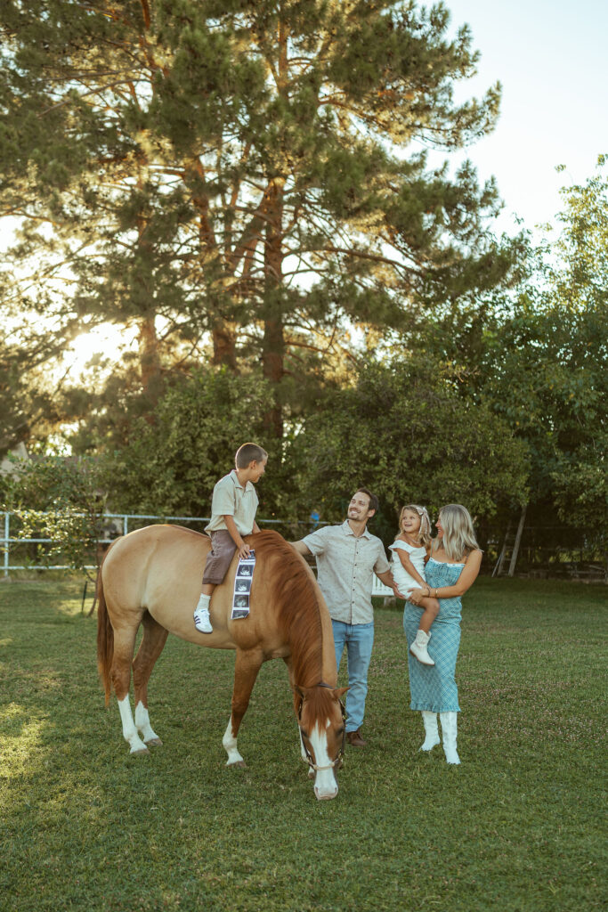 Gilbert maternity photographer documenting parents and children smiling together beside their family horse during an outdoor pregnancy session.