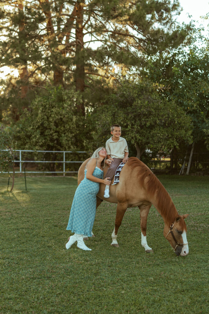 Lifestyle maternity photography capturing parents and children enjoying playful moments with their horse during a golden hour family session.