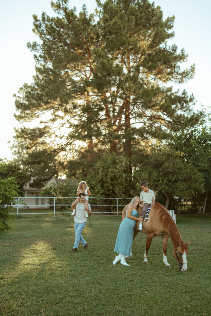 Horse lover maternity photos featuring an expecting mom hugging her son while he sits on their family horse during an outdoor Arizona session.