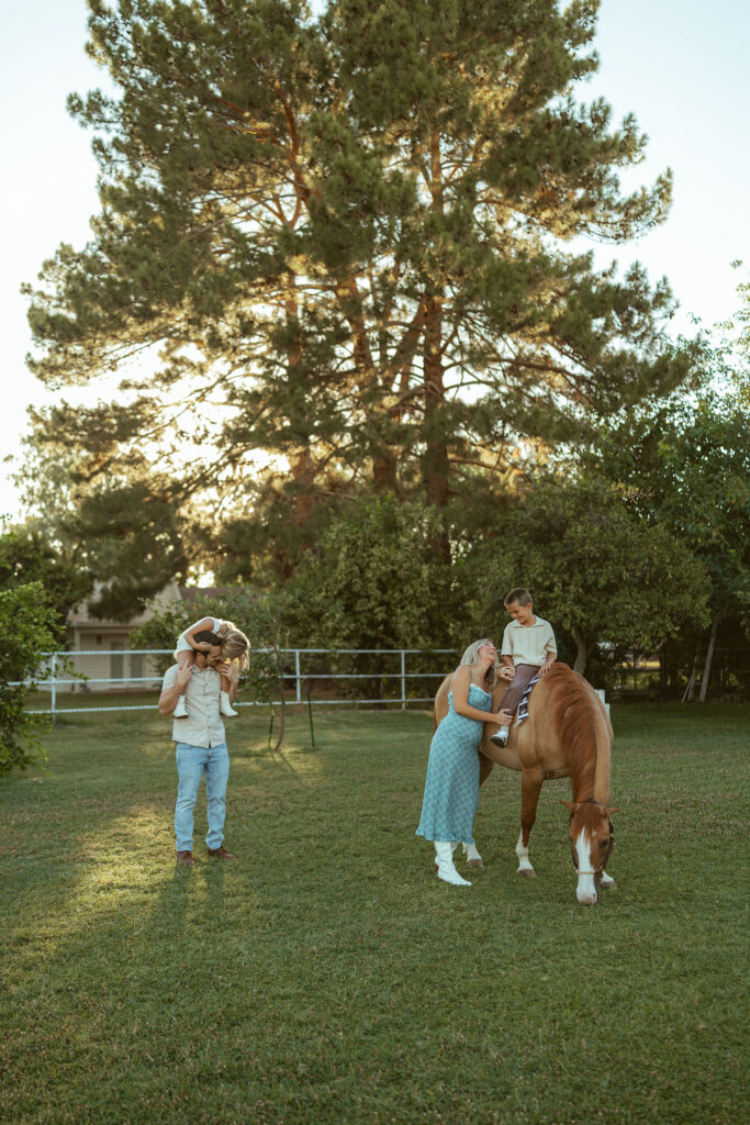 Outdoor family photography showing parents and children spending time together with their horse during a relaxed maternity session at Floyd Family Farms.