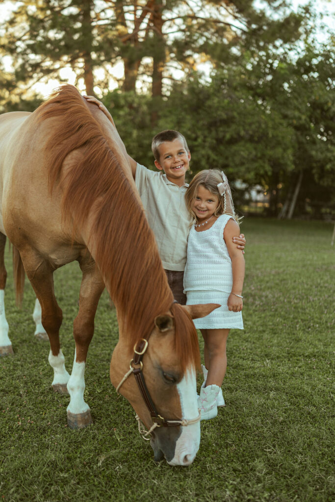Big brother and big sister pregnancy announcement featuring siblings smiling beside their gentle family horse during an outdoor maternity session.