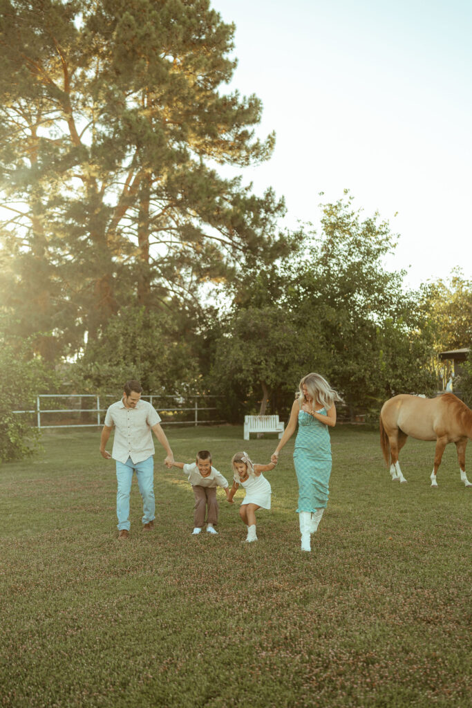 Lifestyle family maternity session featuring parents running hand in hand with their children through Floyd Family Farms during golden hour.