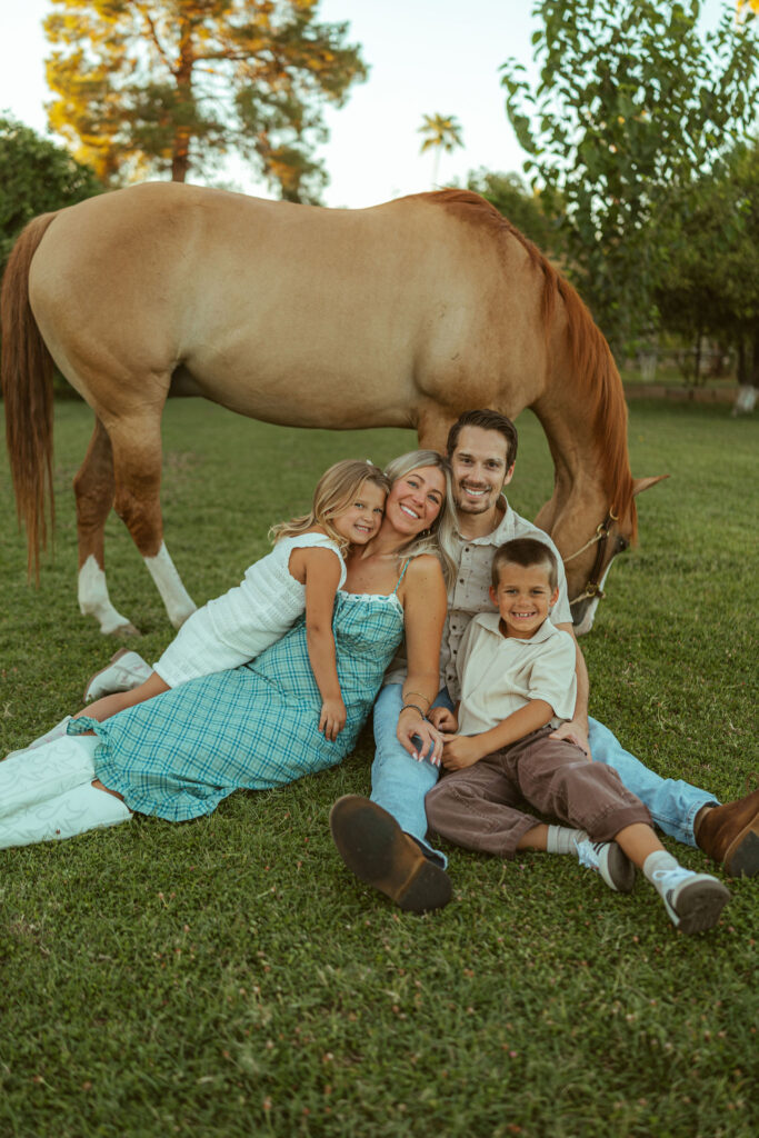 Horse lover family photography capturing parents and children sitting together beneath their horse during a relaxed sunset session at Floyd Family Farms.