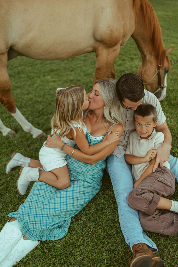 Lifestyle pregnancy announcement featuring an expecting family cuddling together beside their horse at Floyd Family Farms in Gilbert.