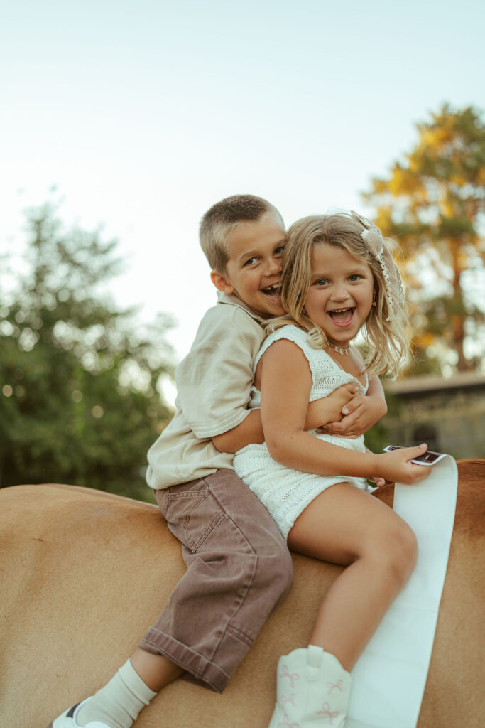 Big brother and big sister pregnancy announcement featuring siblings smiling together while sitting on their gentle family horse in Gilbert, Arizona.