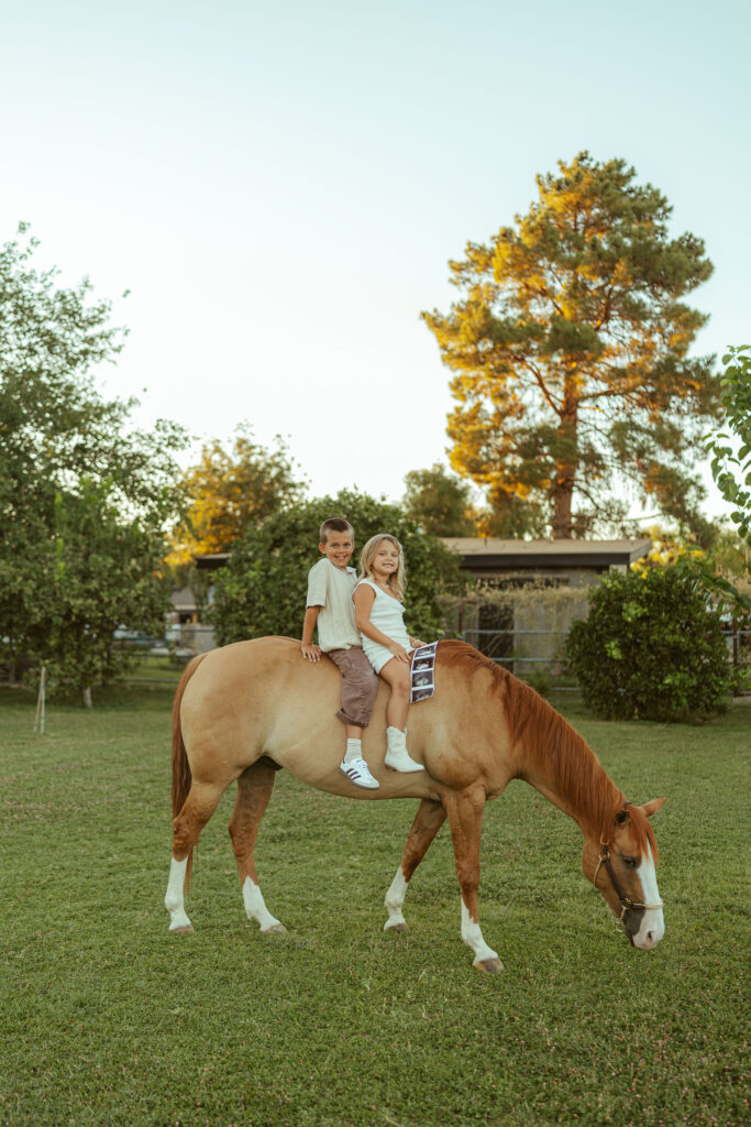 Horseback family photography capturing siblings riding their horse during an outdoor maternity session at Floyd Family Farms in Gilbert.