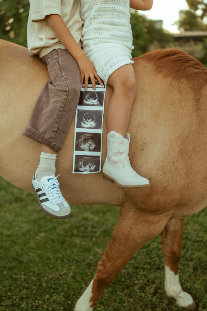 Gilbert maternity photographer documenting an expecting family walking beside their horse through a peaceful pasture at sunset.