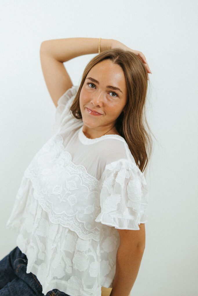 Close-up portrait of an 18-year-old woman in a white textured blouse photographed in a Queen Creek photography studio.