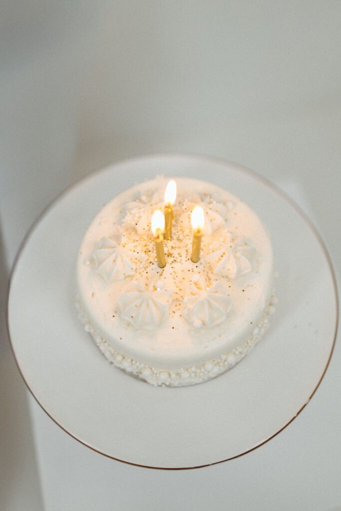 Overhead photograph of a white birthday cake with gold candles and gold sprinkles from an 18th birthday portrait session.