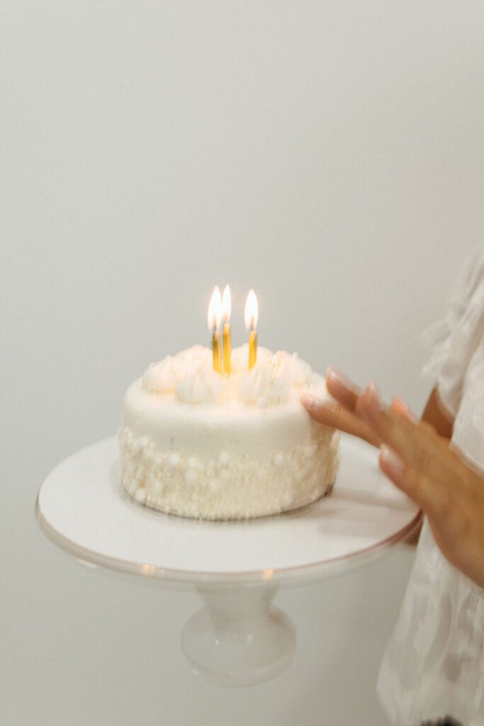 White birthday cake with candles on a cake stand during a Queen Creek 18th birthday portrait session.