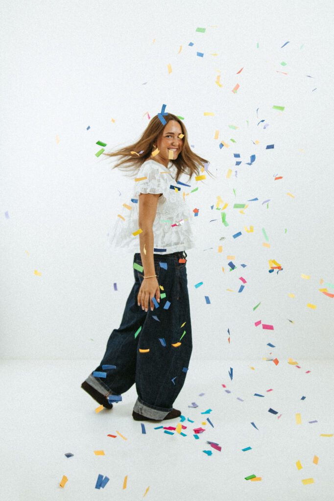 Young woman surrounded by colorful confetti during a fun 18th birthday photography session in Queen Creek.