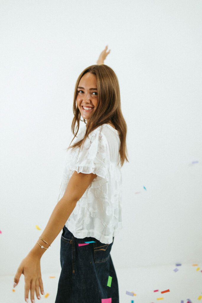 Young woman posing in a white blouse and jeans during her 18th birthday portrait session in Queen Creek.