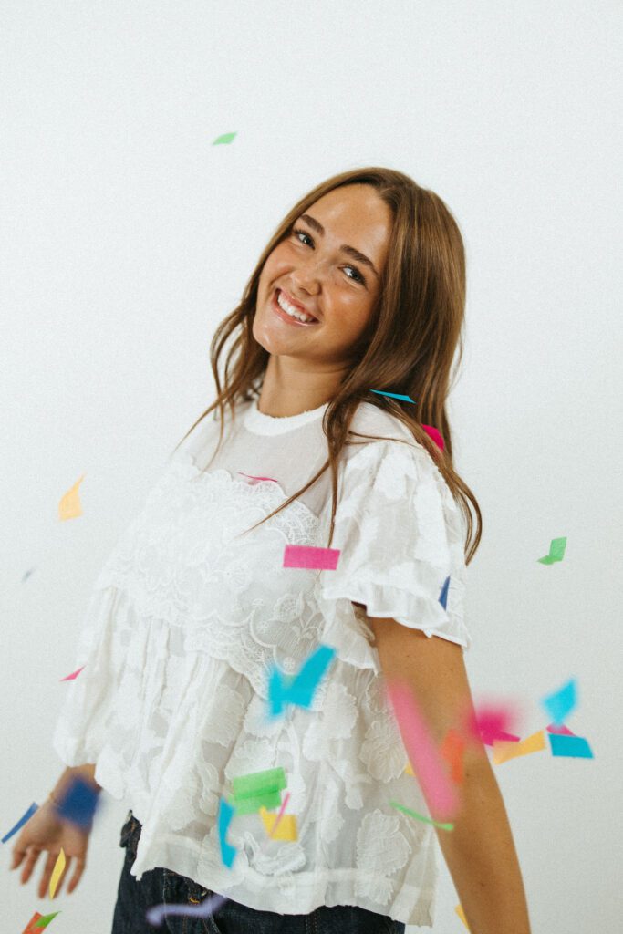 18th birthday portrait of a young woman surrounded by colorful confetti in a Queen Creek photography studio.