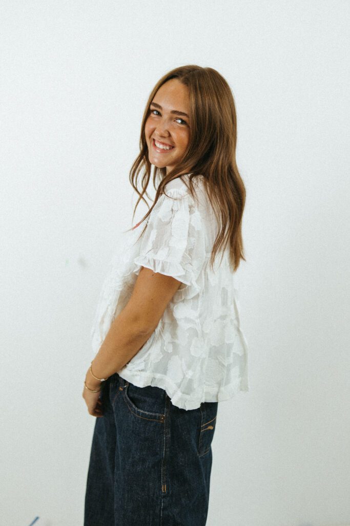 Natural portrait of an 18-year-old woman in a white blouse and jeans photographed in a Queen Creek photography studio.