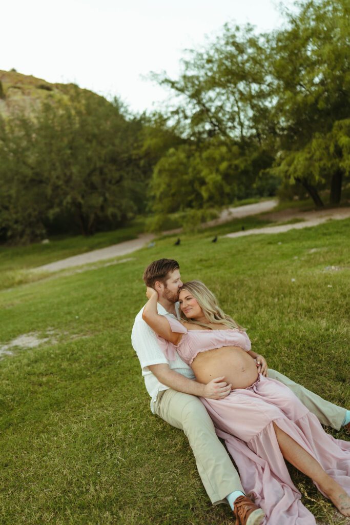 Expecting couple laughing together during their outdoor maternity photography session at Butcher Jones in Mesa, Arizona