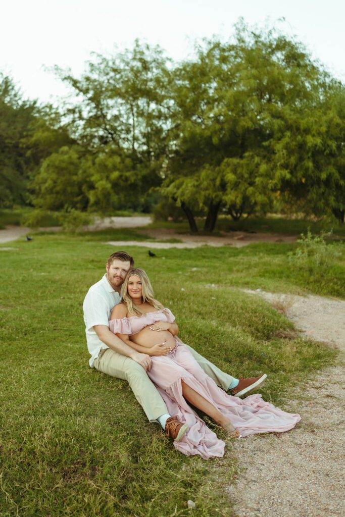 Expecting couple cuddling in the greenery during their Butcher Jones maternity photography session in Mesa, Arizona