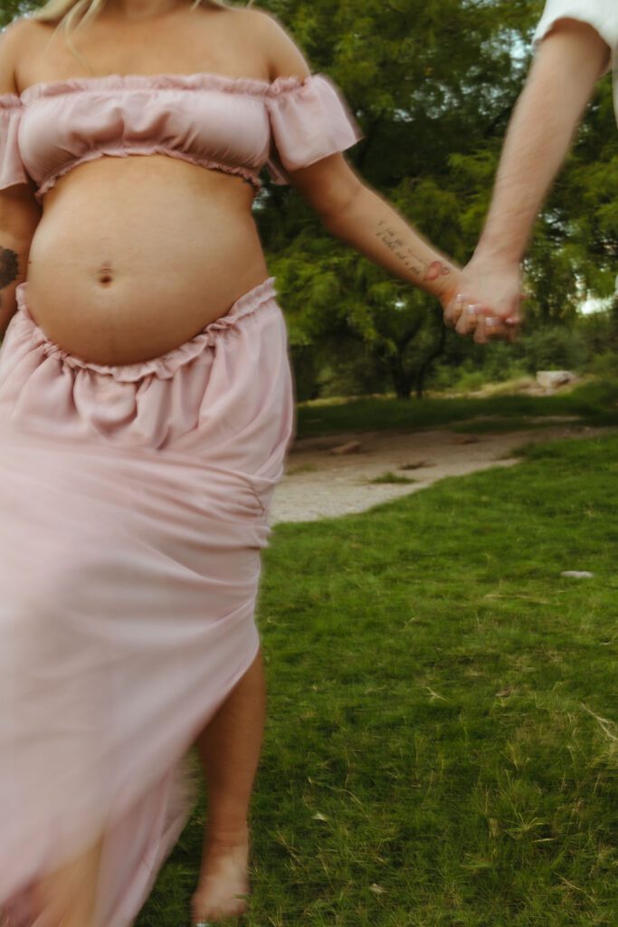 Close-up of an expecting mother holding her partner's hand during a romantic outdoor maternity session near Scottsdale, Arizona