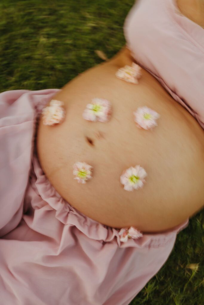 Close-up maternity portrait with pink flowers on an expecting mother's baby bump during an Arizona maternity session at Butcher Jones