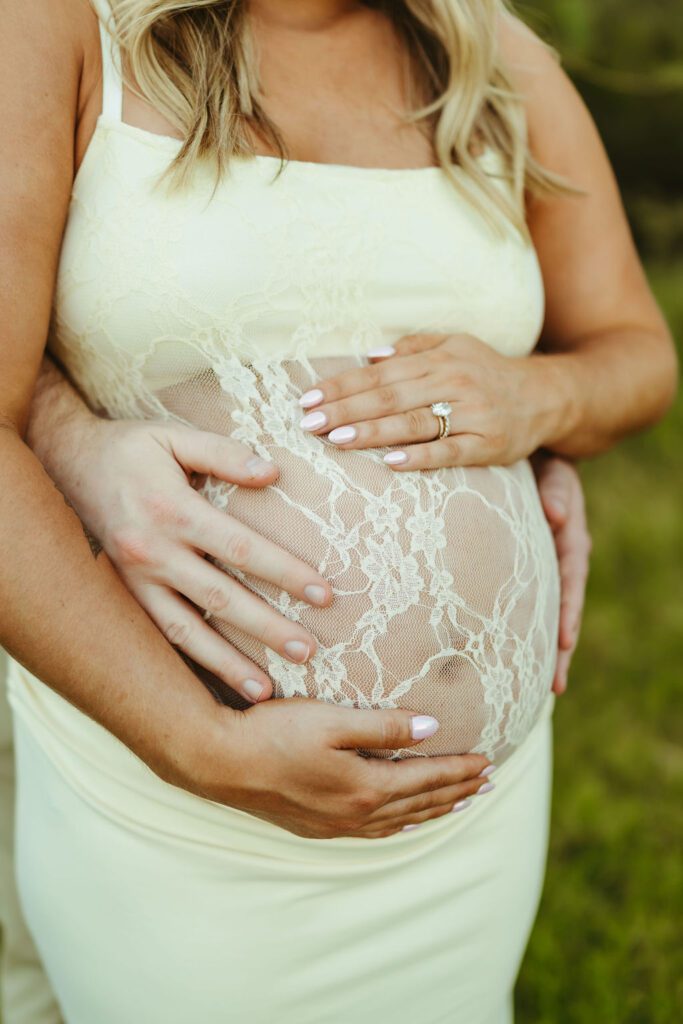 Close-up maternity portrait highlighting an expecting mother's baby bump in a white lace dress during an Arizona maternity session