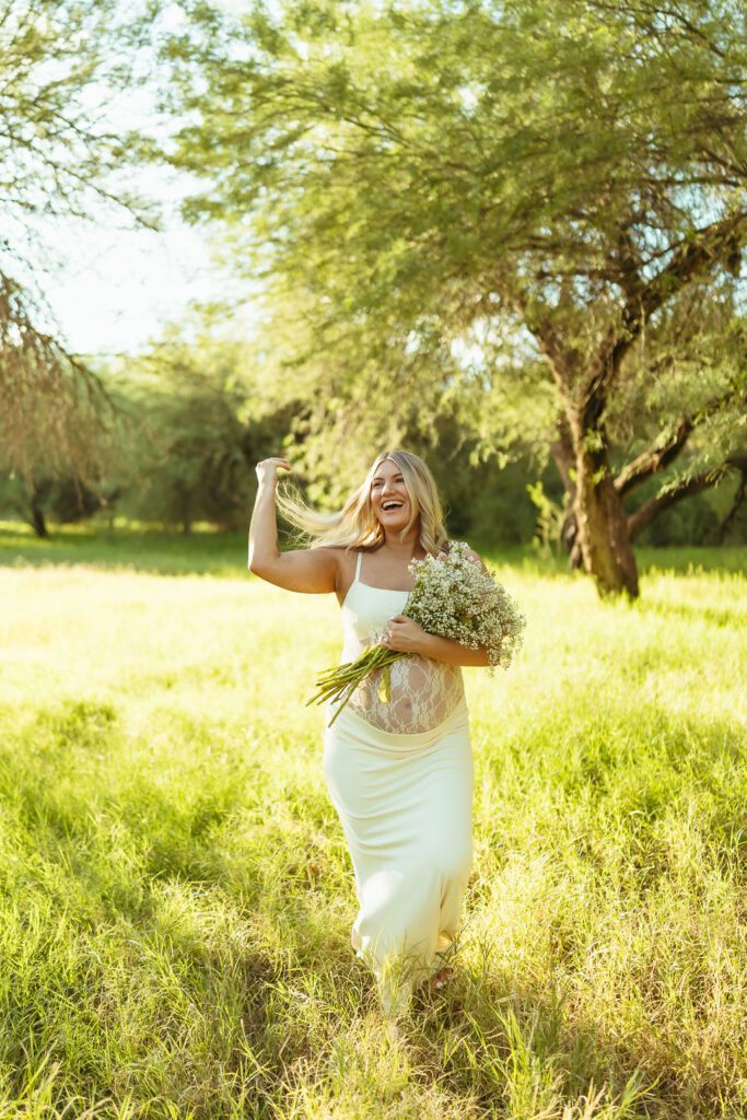 Expecting mother holding a baby's breath bouquet in golden greenery during her Butcher Jones maternity photos in Mesa, Arizona