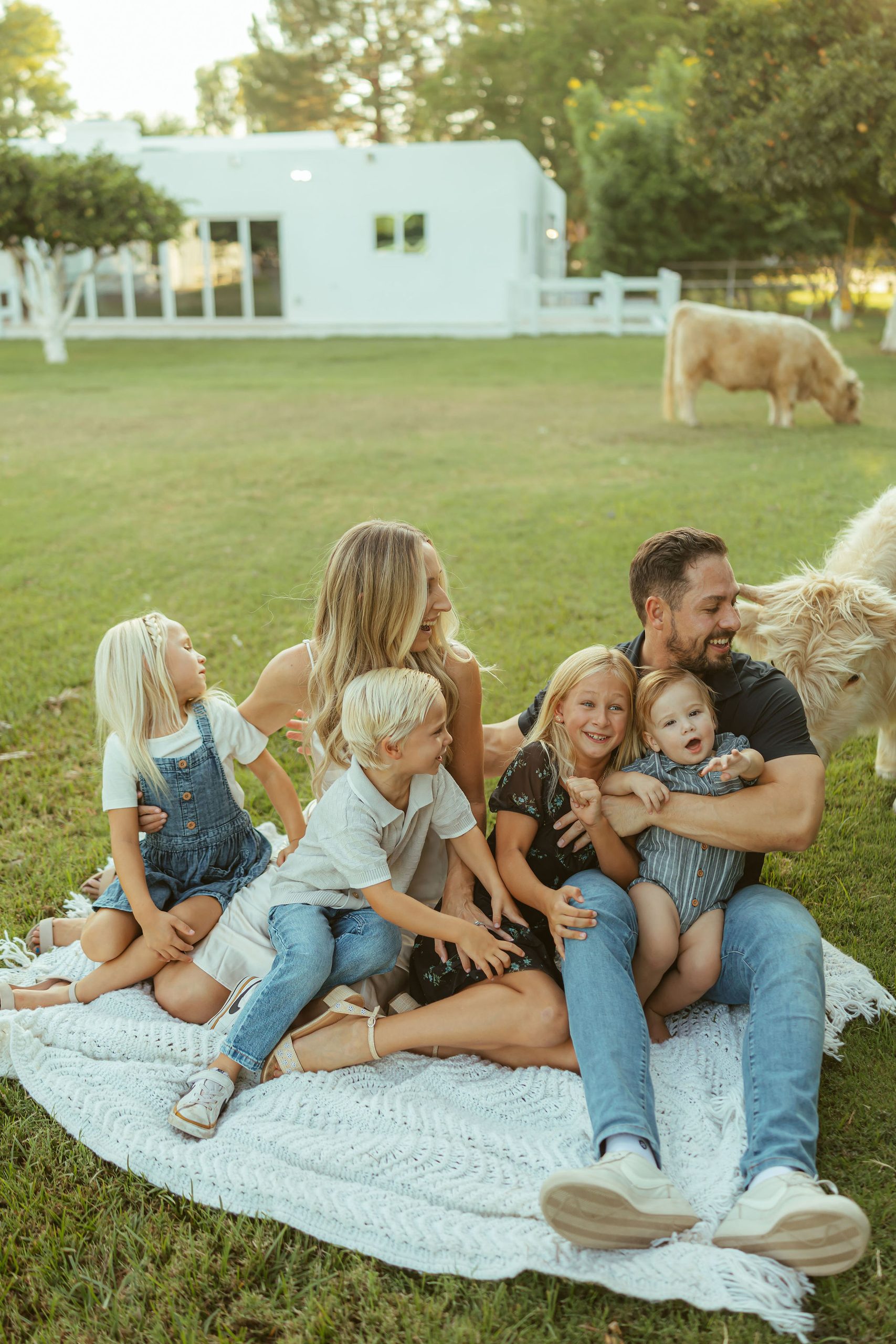 Phoenix family photographer capturing a joyful, tight group hug with a family of seven laughing together in an open grass field at sunset.