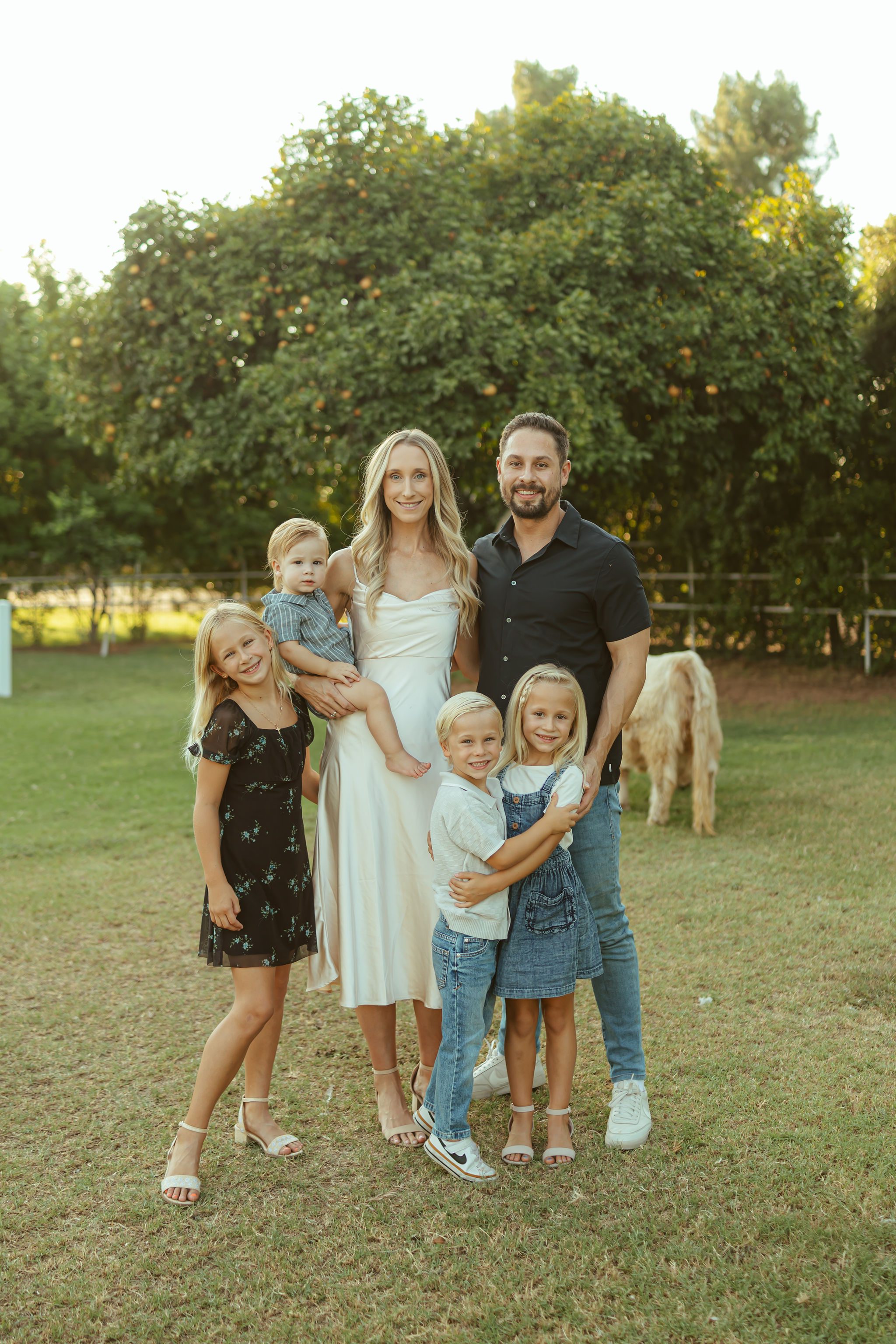 Gilbert family photography featuring a stylish family of seven standing together in a lush pasture at Bloomstead AZ farm.