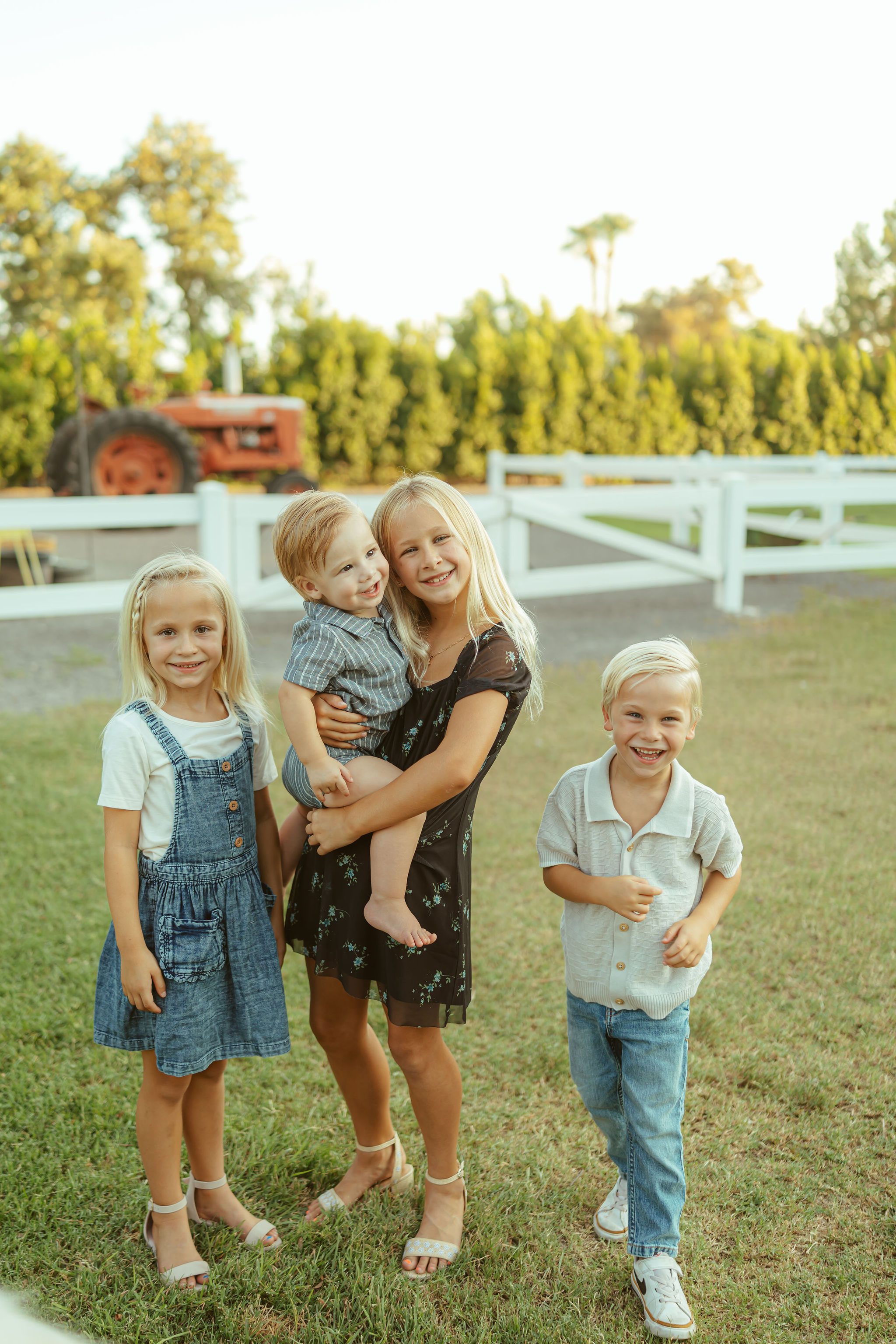 Mesa family photographer capturing a candid, sweet connection between four siblings smiling together during an outdoor farm session.