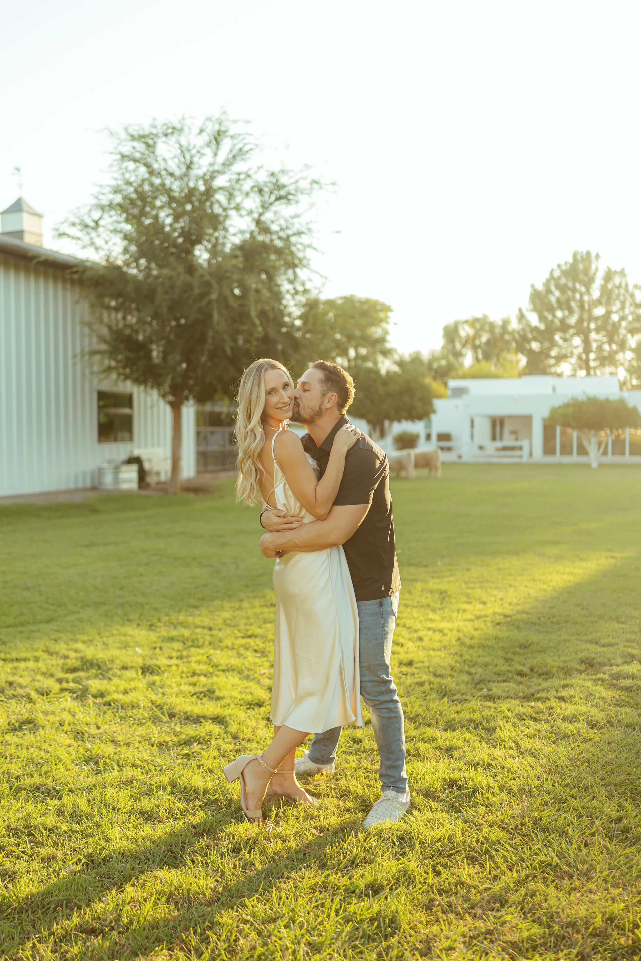 Queen Creek family photography showcasing a romantic, sun-drenched moment of a husband and wife kissing during an outdoor sunset session.