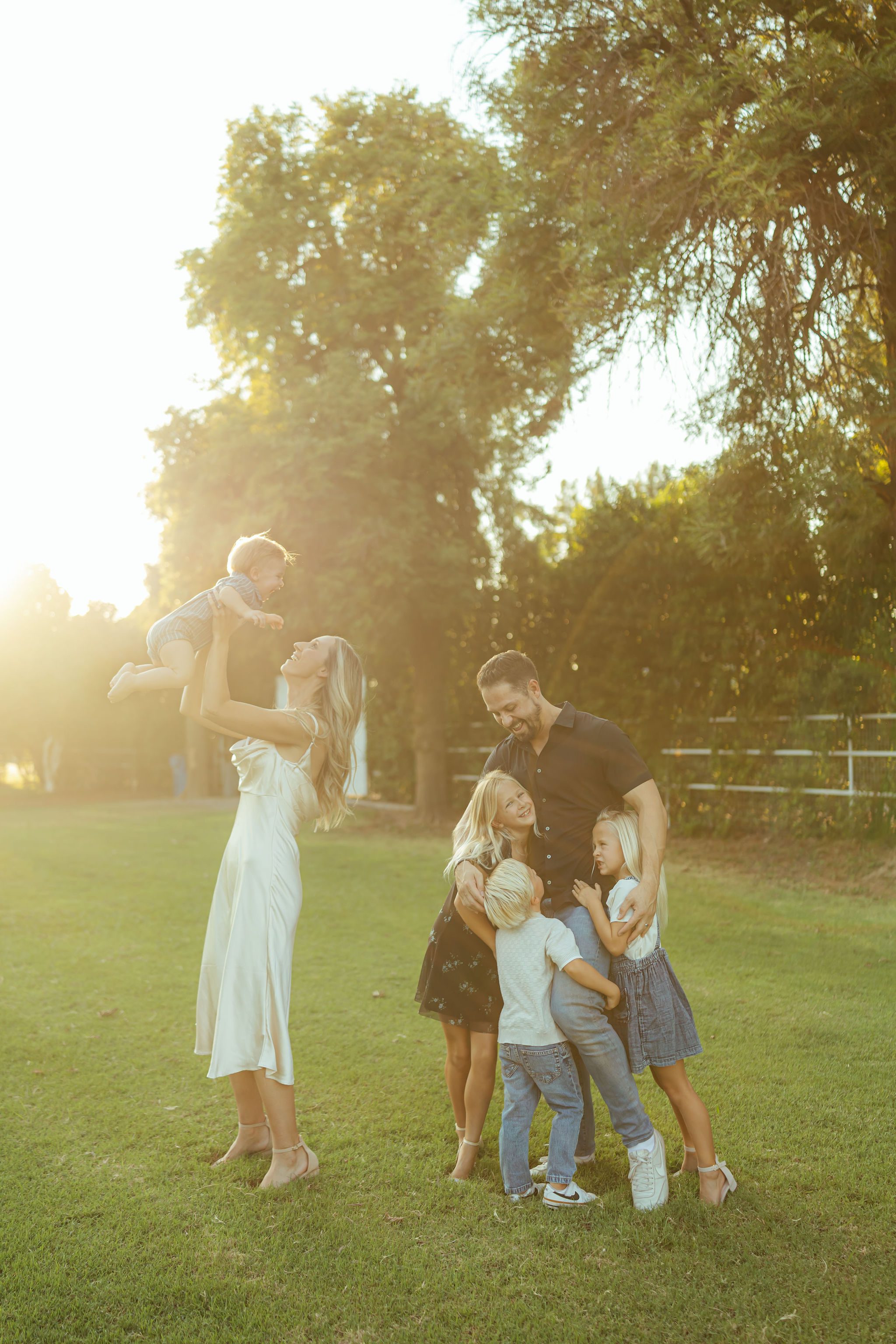 Gilbert family photography highlighting an effortless, sun-drenched moment as a large family interacts naturally in a grassy field at sunset.