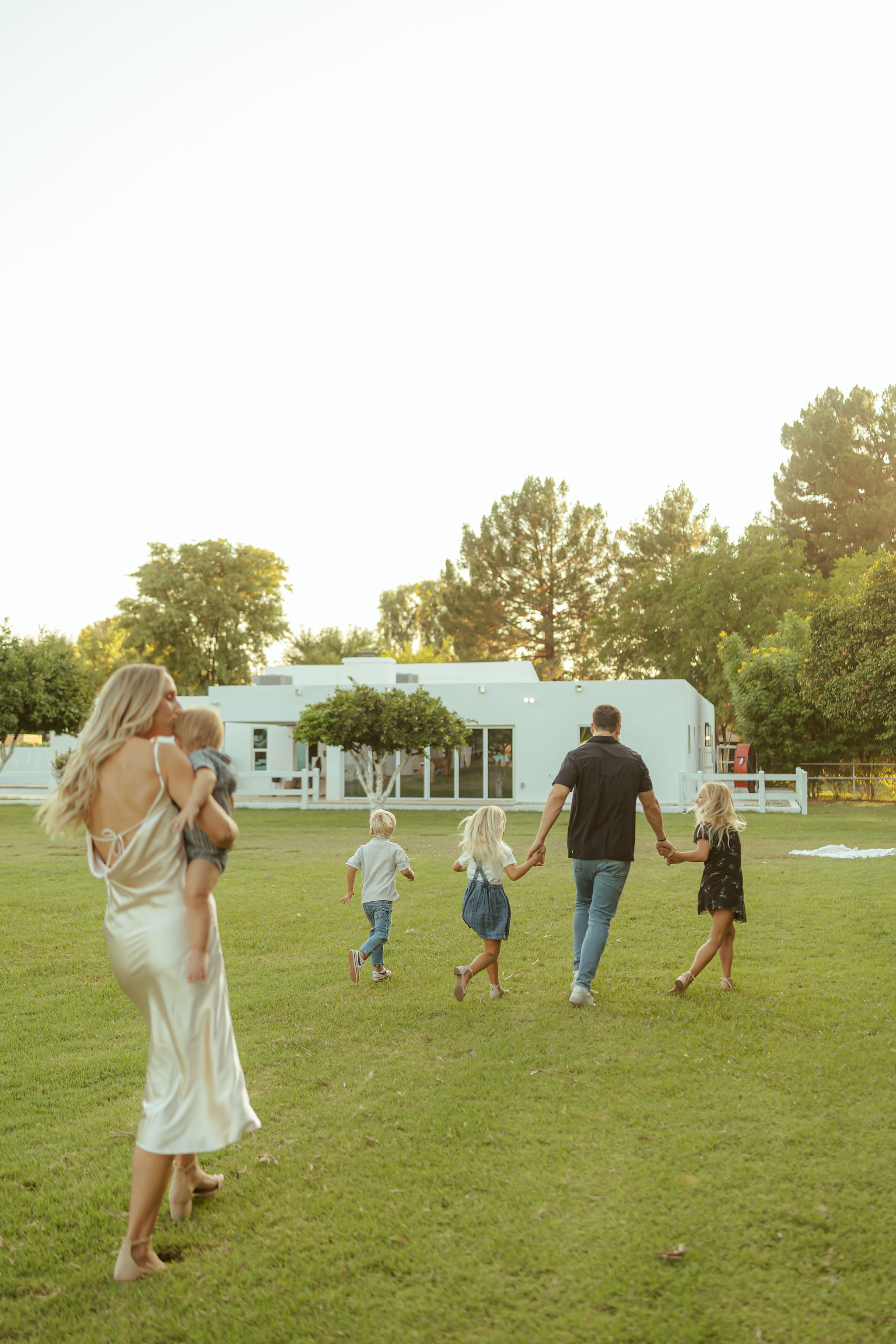 Queen Creek family photography showcasing an effortless lifestyle moment as a family of seven holds hands and walks through a pasture at golden hour.