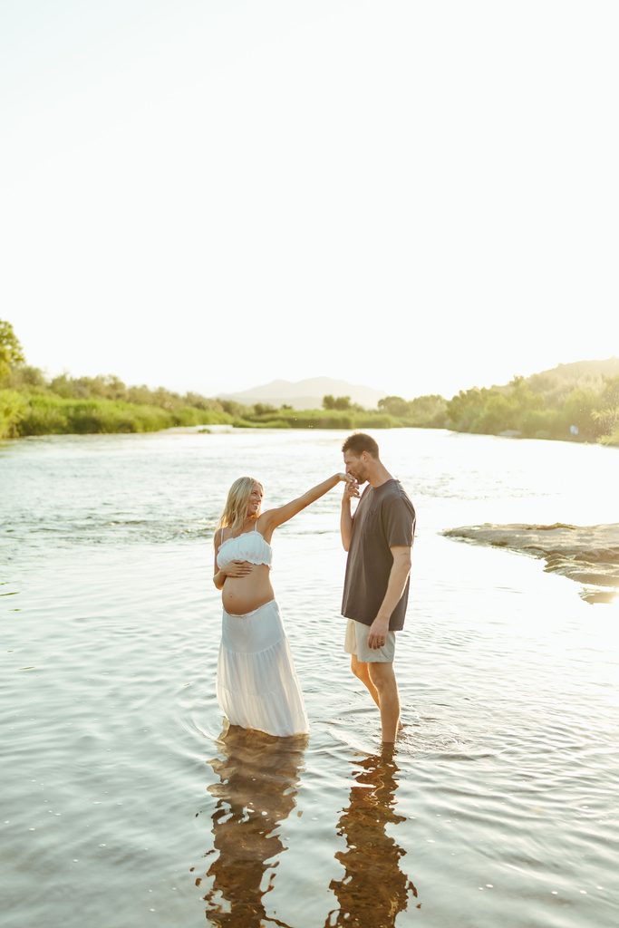 Pregnant couple standing in the Salt River during golden hour in Mesa, Arizona