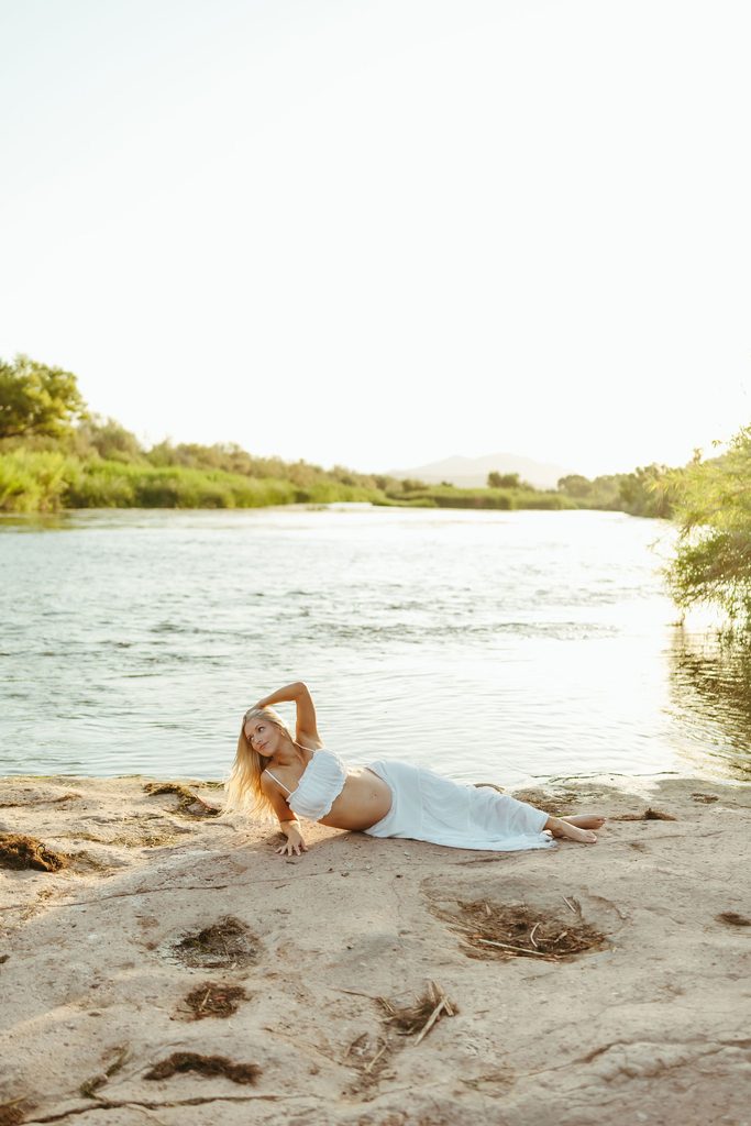 Pregnant woman posing on the Salt River shoreline during a golden-hour maternity session in Mesa, Arizona