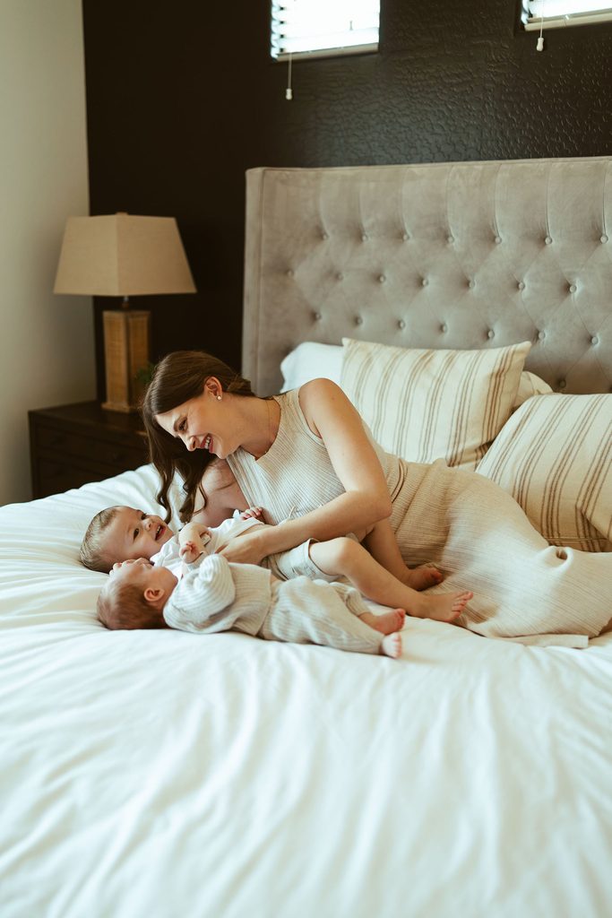 Gilbert newborn photography featuring a mother cuddling her newborn baby on the bed during a relaxed in-home newborn session in Gilbert, Arizona.