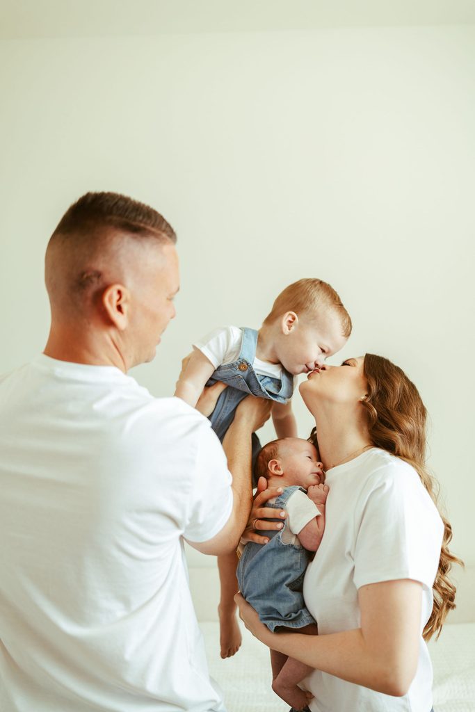 Gilbert newborn photographer capturing parents interacting with their newborn and toddler together during a natural family moment at home.