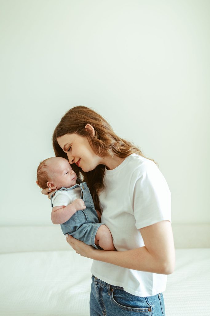 Gilbert newborn photographer capturing newborn siblings lying together on a bed during a beautiful in-home newborn session in Gilbert, Arizona.